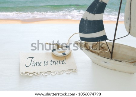 nautical concept image with white decorative sail boat with note over white wooden table
