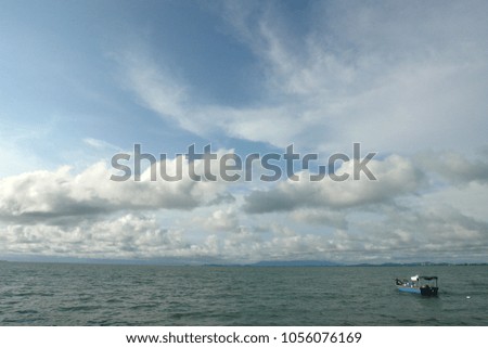 Stunning view of the sea with blue skies and puffy clouds with a little boat                                