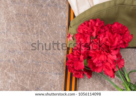 St. George ribbon lies on a background of textures with an inscription, with carnations and military cap