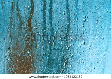 Frozen glass of window from inside of room. Background in cool tone with texture of dripping water drops
