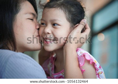 Mother kiss daughter cheeks.
