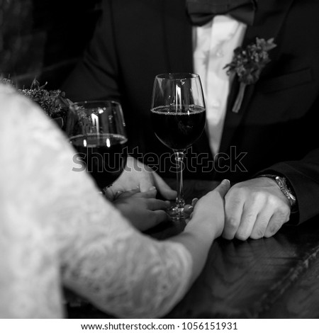 Glasses with wine in bride and groom hands. Happy newlyweds drinking. Loving couple created new family. Black and white image