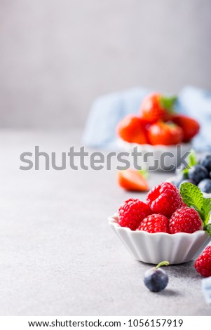 White ceramic bowl with fresh healthy berries. Raspberry, strawberry and blueberries. Copy space.