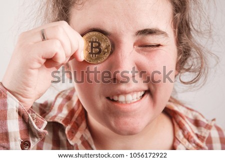 crazy bitcoin lover with golden coin by eyes; funny miner with btc near face