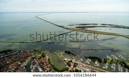 Aerial view of the dike to Lelystad, Flevoland, as seen from the city and harbour of Enkhuizen in The Netherlands. The highway divides lake IJsselmeer and Markermeer. It is a beautiful clear day.