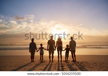 Rear View Of Multi Generation Family Silhouetted On Beach Royalty-Free Stock Photo #1056219500