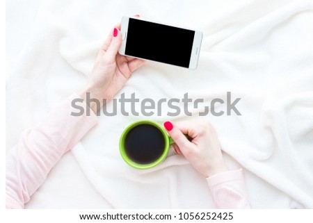 woman uses white smart phone, women's hands, lying on the blanket, red manicure, white background with copy space, for advertising, top view