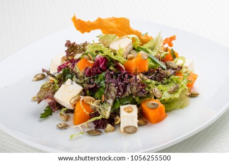 Salad with pumpkin and feta on a white background. Vegetarian