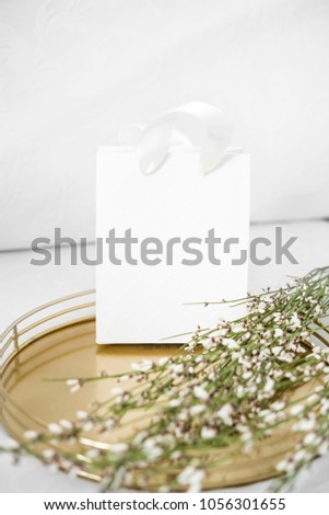 Lifestyle composition with white gift bag and gold notebooks, on white background