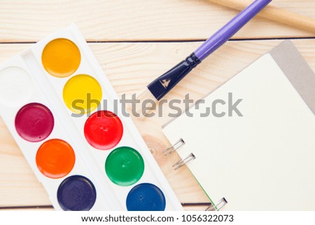 Paints with pencils and colorfull markers on wood board background. Education or business photo. Take note of the product for book with paper and concept or copy space.