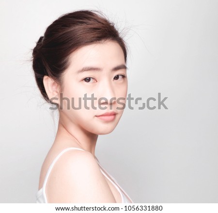 young asian girl with clean skin, Cosmetic Beauty Concept,hands touch on the cheek, smiling and friendly face isolated on grey background