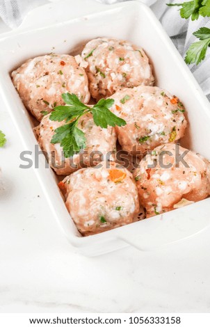 Raw homemade chicken or turkey meatballs in baking dish on white marble background. Copy space
