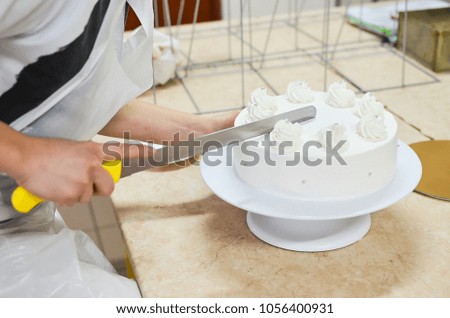Hand confectioner special confectionery knife cut a beautiful white cake in the kitchen