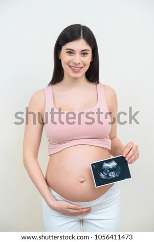 smiling young pregnant woman with ultrasound scan picture of baby