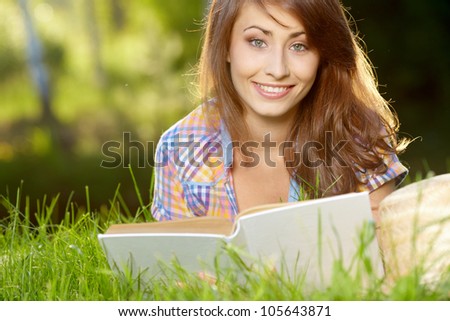  female student lying on the grass with a books