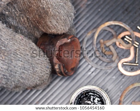 technician hand in glove holds automotive parts disassembly, inspecting universal joint from sport utility vehicle drive shaft show dried out defect broken bearing and rustic surface need replacement