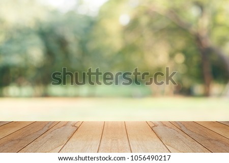 wooden table in front of abstract blurred background of park Royalty-Free Stock Photo #1056490217