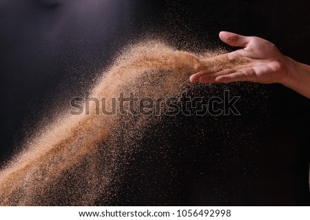 sand explosion with right hand on black background Royalty-Free Stock Photo #1056492998