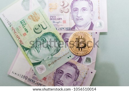 Gold Bitcoin with actual Singapore Dollar currency banknote indicating dangerous of cryptocurrency
