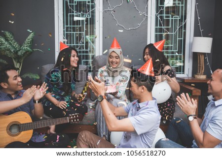 portrait of happy young asian people celebrating and singing birthday of their friends together at home