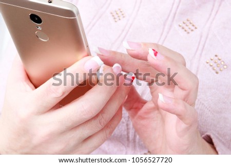 Womans hand holding gold smartphone against window