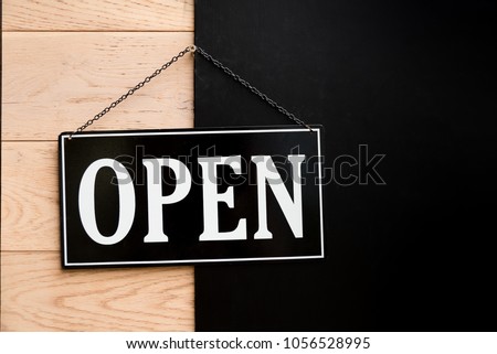 Open sign hanging on wooden wall in restaurant.
