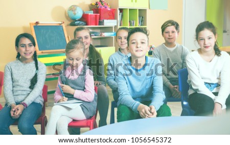 Nice boys and girls  listening teacher, sitting at lesson  in classroom