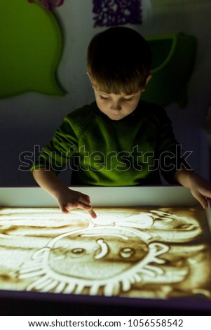 The boy draws sand in the sand