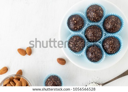 Chocolate energy bites with nuts, cocoa powder, dates and coconut flakes. Top view with copy space. Royalty-Free Stock Photo #1056566528