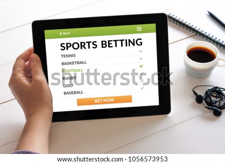 Hand holding digital tablet computer with sports betting concept on screen. All screen content is designed by me