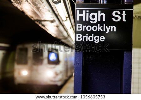Subway train approaching behind the sign depicting it's the High St. Brooklyn Bridge station in Brooklyn, New-York.