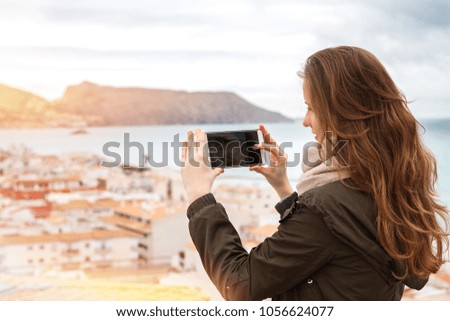 The beautiful girl photographing a cityscape on phone.