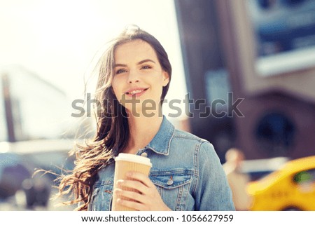 drinks and people concept - happy young woman or teenage girl drinking coffee from paper cup on city street