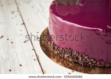 dark chocolate vegan cake with cream and fruit mirror glaze on wooden background