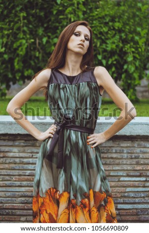 Young beautiful girl with brown-haired woman in dress walking walks in park in nature and posing. Fashion photo