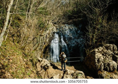 man with backpack taking pictures of the waterfall