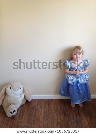 Blond haired girl plays dress up as  Disney princess with Easter rabbit soft toy