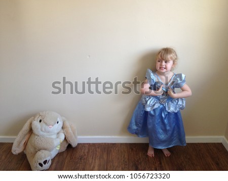 Blond haired girl plays dress up as  Disney princess with Easter rabbit soft toy