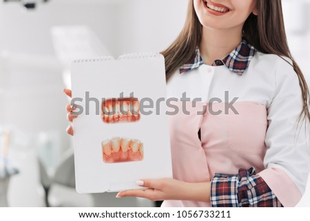 Young female dentist showing picture of teeth in her office.
