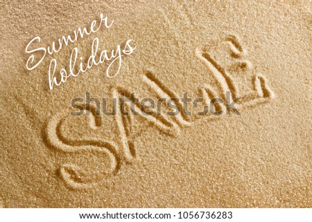The word sale is painted on the sand and the inscription is a summer holiday. Beach background. View from above. The concept of summer, summer kanikkuly, vacation, holydays.