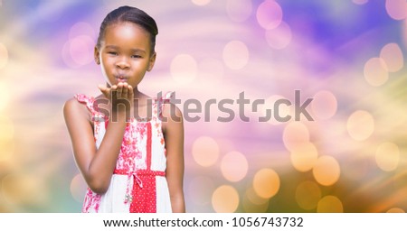 Digital composite of Little girl giving flying kiss over blur background