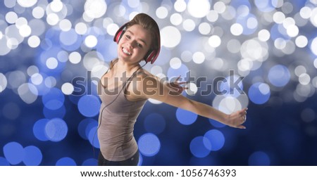 Digital composite of Happy woman dancing while listening to music on headphones against bokeh