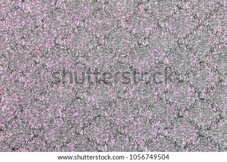 Knitted gray-lilac texture. Beautiful background with patterns in the form of a rhombus of the loops. Beautiful needlework.