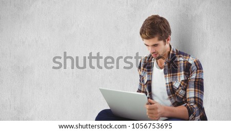 Digital composite of Young man using laptop against wall
