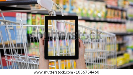 Digital composite of Hand taking picture of shopping cart with tablet PC in grocery store