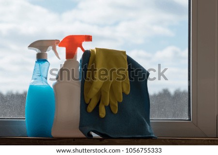 Bottles with cleaning agents stand on the window sill against a dirty window.