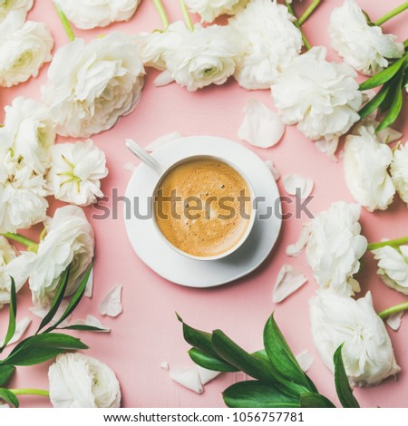 Spring morning concept. Flat-lay of cup of coffee surrounded with white ranunculus flowers over light pink pastel background, top view, square crop