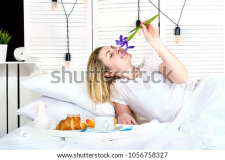  Beautiful young woman having breakfast in bed. Surprise from beloved husband. Celebrating a woman's day, mother's day.