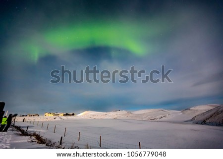 Aurora Borealis shimmers through the clouds during winter night 
