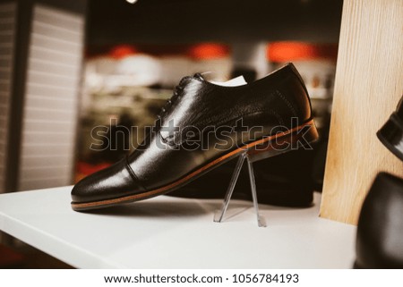 Stylish leather / lacquered men's shoes on the shelf in the store. Black / brown men's shoes on the stand. Male style, fashion. Gatherings of the groom. vintage photo processing